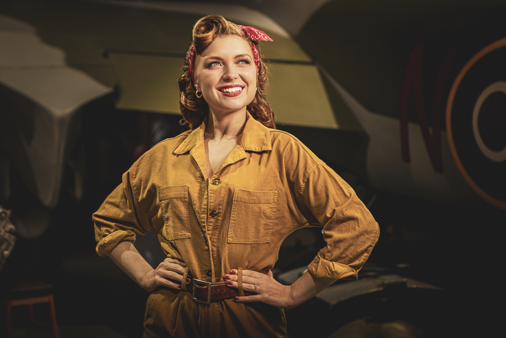 Felicity Furore, burlesque artist, poses for a photograph beside a warplane in an aircraft hanger.