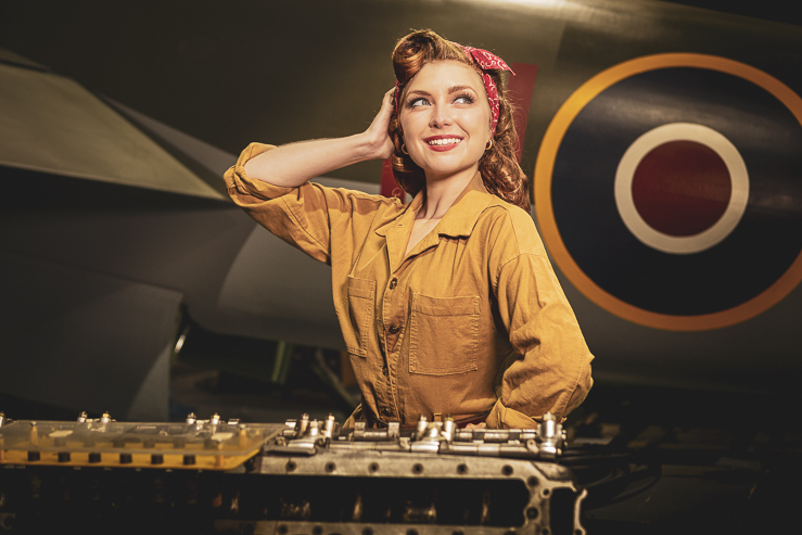 Felicity Furore, burlesque artist, poses for a photograph beside a warplane in an aircraft hanger.