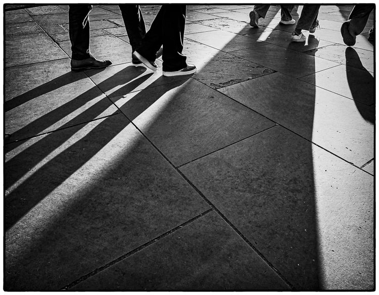 Long shadows cast of feet walking through London